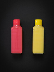 Pink and yellow plastic bottles on a black background.
