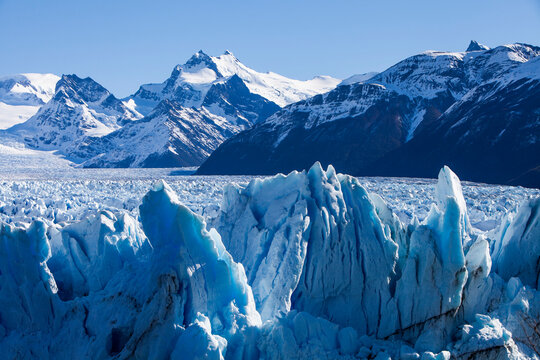 Closeup of ice rocks surrounded by snowy mountains at Perito Moreno Glacier in Argentina. Global warming and climate change concept.
