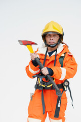 A portrait of Asian male fireman in red protective clothing, mask and helmet with an ax standing on a white background.