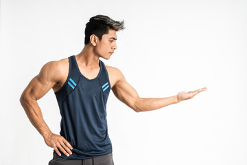 Muscular young Asian man in sportswear stands sideways with present something on his hand on a...