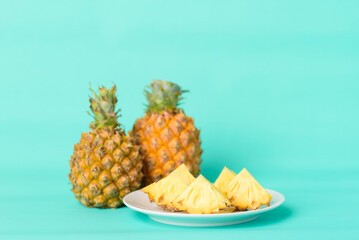 Sliced pineapple fruit on plate with pastel green background, Tropical fruit