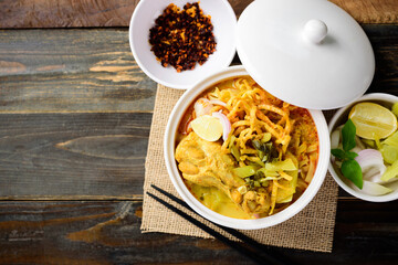 Northern Thai food (Khao Soi), Spicy curry noodles soup with coconut milk and chicken eating with crispy egg noodles, pickled mustard, shallots, lime and fried chili in oil