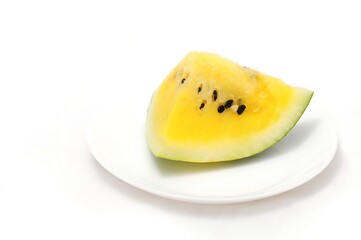 Cut piece of yellow watermelon on a white plate on a white background
