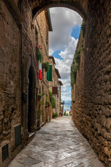 Iconic and narrow tuscanian back alley leading to a vantage point on the countryside below, with italian flags hanging from the windows