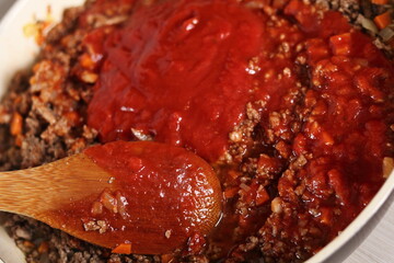 Mixing tomato paste and minced meat