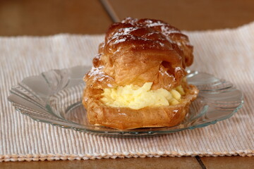Eclair filled with pastry cream (custard) and topped with icing sugar