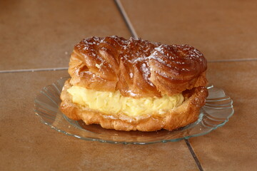 Eclair filled with pastry cream (custard) and topped with icing sugar