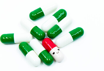 Smiling face red capsule medicine with green normal capsules on the white background. The concept of a novel drug development against rare diseases