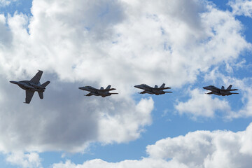 Four modern air force fighter aircraft approaching the airbase in formation.