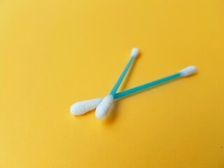 Ear cotton buds are blue on a yellow background. Cosmetology and medicine. Personal hygiene and care.