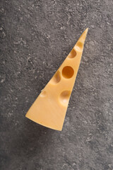 Piece Maasdam cheese on concrete gray background. top view