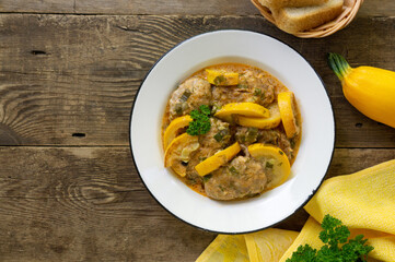 Meat cutlets with zucchini in tomato sauce on a wooden background