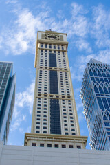 Naklejka premium Dubai International Financial Centre (DIFC) Iconic The Tower (clock) amid modern Dubai skyscrapers on blue sky.