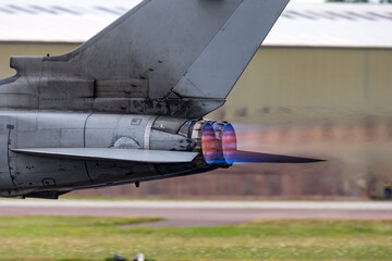 Afterburners glowing on an air force fighter jet aircraft as it speeds down the runway of an air...