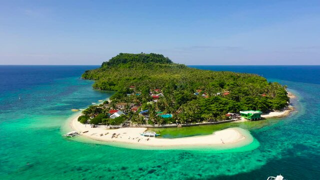 Himokilan Island, Leyte Island, Philippines. Tropical island with a village and a white beach. Turquoise water and coral reefs around the island. Summer holiday vacation concept.