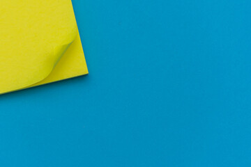 Bright yellow posted note on bright blue flat lay background for education or business organization...