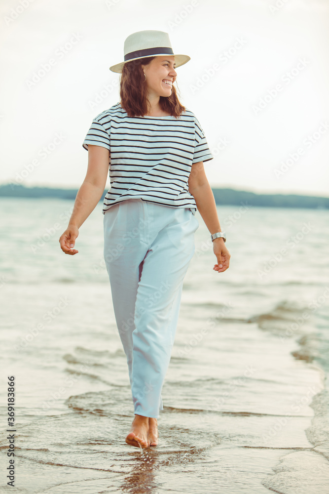 Wall mural woman in white clothes walking by sea beach