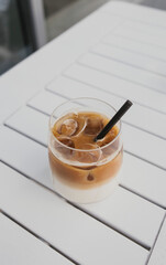 Glass of iced coffee on white table on cafe terrace.