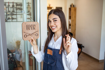 Opening small business after covid-19 pandemic. Closeup on smiling middle aged small business owner woman in apron with crossed fingers showing open sign.