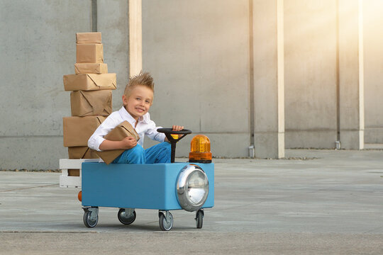 A Boy In A Toy Car Is Carrying Boxes.