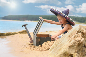 A treasure hunt on the beach. Little boy is playing on the beach in summer.