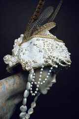 Naklejka premium Head of mannequin in creative white headwear with feathers and pearls