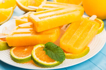 Homemade frosty popsicles with oranges on a blue wooden background