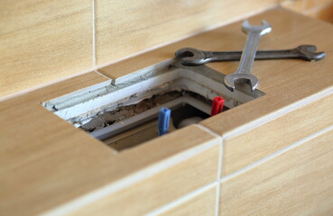 Broken mechanism of modern toilet cistern, open toilet cistern and two metal spanners / wrenchs close up