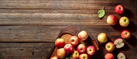 Red apple and wooden board on rustic wooden background. Ripe apples on vintage table and copy space. Summer or autumn season.
