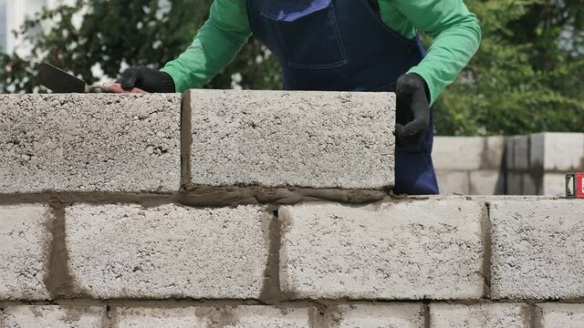 Mason Puts the Brick of Outer Wall of Building. Bricklayer Installation of Concrete Blocks