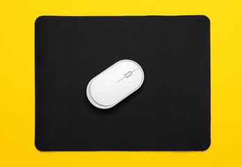 Modern computer mouse with mat on color background
