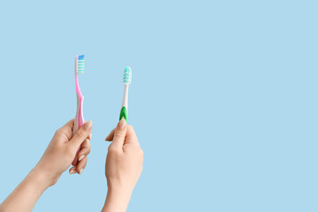 Hands with tooth brushes on color background