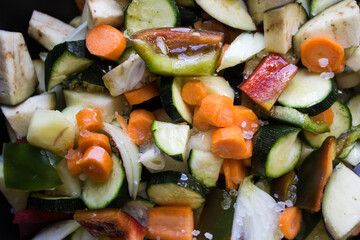 closeup of courgettes, carrots, peppers, onion, eggplants and garlic cut ready to be cooked 
as the basis for a vegetarian couscous