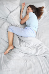 Young woman sleeping in bed, top view