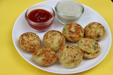 Appum or Appe, Appam or Mixed dal or Rava Appe served with green and red chutney. A Ball shape popular south Indian breakfast dish, Selective focus