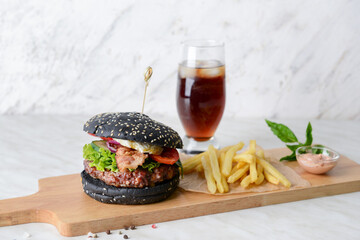 Tasty burger with black bun, french fries and cola drink on white background