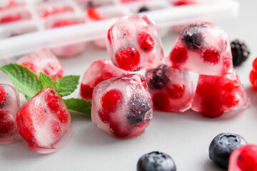 Ice with frozen berries on light background