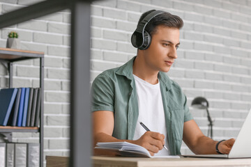 Man with headphones and laptop working in office