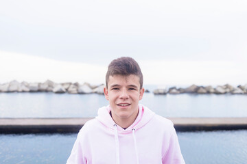 Young teenager male standing on rock breakwater while looking at camera