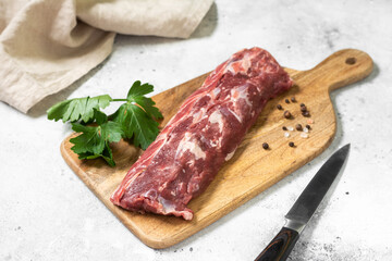 Lamb meat. Young lamb meat on a wooden Board on the light gray kitchen table. Raw lamb meat and cooking ingredients. Lamb tenderloin