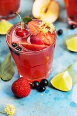 Red cocktail with slices of apple, strawberry and currant