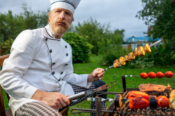 Chef prepares vegetable and meat on the grill. Outdoor barbecue