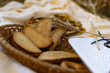 An edible composition of flour baking in a basket on a bedspread, among Golden ears of barley in nature. A big fat donut, vanilla crackers and bagels round