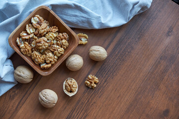 Fototapeta na wymiar Walnuts kernels on dark desk with color background, Whole walnut in wood vintage bowl.