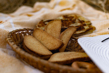 An edible composition of flour baking in a basket on a bedspread, among Golden ears of barley in nature. A big fat donut, vanilla crackers and bagels round