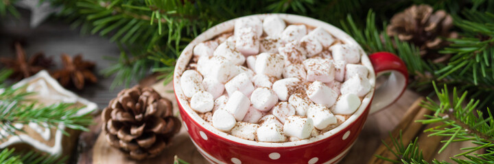Cocoa with marshmallows on a new year's background. A Cup of cocoa on the background of a Christmas tree and ornaments. Banner