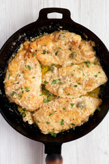 Homemade Italian Chicken Piccata in a cast iron pan, top view. Overhead, from above, flat lay. Close-up.