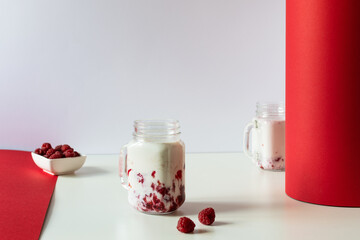Raspberry milkshake on creative red and white background.