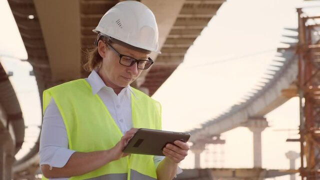 Woman foreman working on construction site using tablet.
