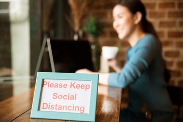 Woman drinking coffee in a coffee shop where social distancing is required